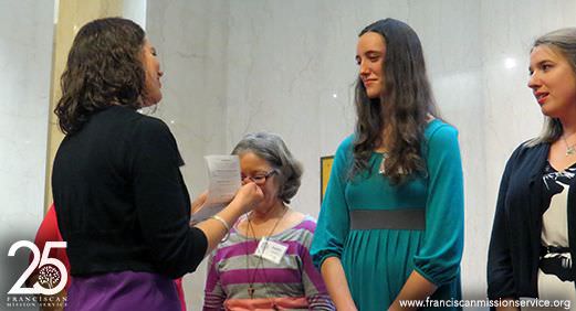 Programs Manager Emily Norton bestows missioner-in-training Erin McHugh with her Tau cross